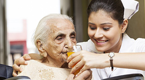Care worker helping an older woman drink at home